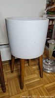 White ceramic planter pot on wooden stand taken from front
