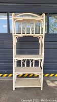 Full front view of five-tier rattan shelf against dark background