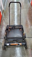 Full view of the Remington 18-inch reel lawn mower showing handle, grass catcher, and front roller with brand label.