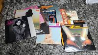 Photo of 8 vinyl classic rock record albums displayed on a grey carpet, showing various album covers.