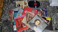 Photo showing a variety of vinyl record albums on a carpet, including George Strait, Rod Stewart, Alabama, R.E.M, and Christmas themed albums
