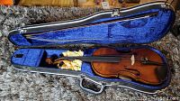 Violin inside open hard case with bow on blue velvet lining