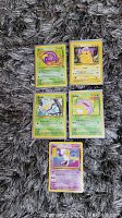 Five Pokemon cards laid out, including Pikachu, Ekans, Gyarados, Slowpoke, and a holographic Mew card promotional from 2000