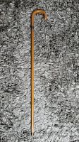 Full view of wooden walking cane with curved handle on carpet background