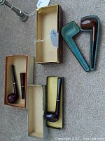 Overview of three pipes and their original boxes on carpet