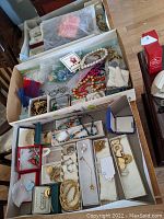 Overview of three shallow trays showing assorted necklaces, bracelets, earrings, rings, pendants and brooch.