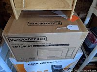 Boxed Black & Decker microwave oven showing brand and model details.