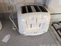 White Krups 4 slot toaster on kitchen counter with cords, control knobs, and buttons visible