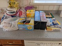 Photo of assorted disposable paper plates stacked and packaged vacuum storage bags on kitchen counter.