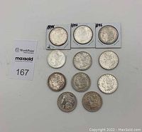 Eleven 1896 Morgan silver dollars arranged obverse up, three in cardboard flips at top.