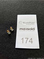 Pair of small earrings with pale blue rectangular stones and 14K gold prong setting shown next to MaxSold number card.