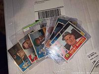 Nine 1960 Topps baseball cards fanned out in protective sleeves, showing card fronts with various players, close-up exposure of card condition, cards approximately 2 x 3 inches each.