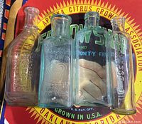 Four antique medicine bottles grouped showing embossed brand names and different bottle shapes on colorful background.