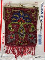 Full view of the front of the beaded antique purse showing intricate multicolor beadwork, gold-tone metal frame, and chain handle, with red beaded fringe at bottom.