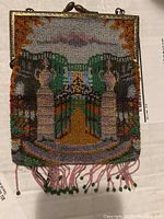 Front view of antique glass beaded purse depicting French garden scene with mansion, detailed beadwork, and beaded fringe