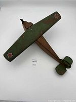 Top view of antique Steelcraft Army Scout Plane metal toy showing green wing with army star decals and rusty brown fuselage with detached wing.