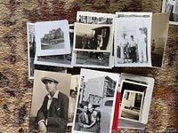 Overall lot of early black and white photos and postcards scattered on carpet, showing diverse subjects including men, women, children, buildings, and vehicles, in various outdoor and posed settings.