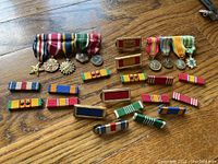 Top view of all the mini medals, ribbon bars, and two tour stars spread on wood surface.