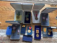 Overview of US Army medals with various ribbons and boxes, arranged on wooden surface