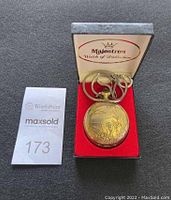 Front view of the quartz pocket watch in Majestron branded presentation box with visible hunting scene embossed design and attached chain.