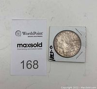 US 1883-O Morgan Silver Dollar coin with auction lot card number 168. The coin is stored in a white cardboard holder secured with staples.