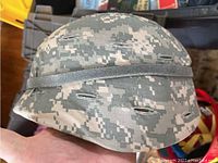 Side and top view of US Army digital camouflage helmet showing ventilation holes and fabric pattern.