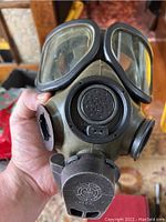 Front view of olive green MSA respirator mask showing dual clear eye lenses, voice diaphragm and filter intake port.