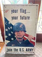 Front view of the metal recruiting sign showing soldier with helmet, American flag in background, and recruitment text. Sign surface shows scratches and wear.