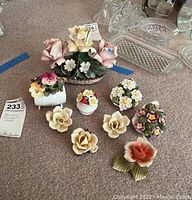 Photo showing an Ansley bone china basket with pink and yellow hand painted flowers, surrounded by multiple bone china flower figurines including roses, daisies, and clusters.