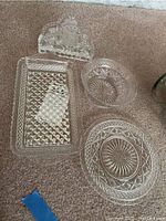 Glass plates, napkin holder, and small glass bowl arranged on carpet