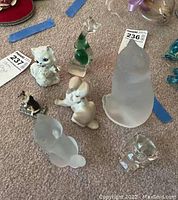 Seven glass and ceramic cat and dog figurines arranged on carpet, showing whole lot