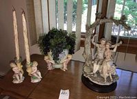 Wide view of cherub candlesticks, ceramic pot with grapes, and resin couple on swing