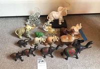 Overview of the elephant lot showing various elephants in different materials including stone, glass, ceramic, and carved black material with decorative paint.