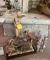Photo showing all four figurines together: naked female with swan, two cherubs, children on see-saw figurine.