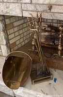 Photo showing brass fireplace tools on stand, brass log holder next to fireplace.