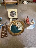 Wide shot showing assortment of religiouss decor including framed art, figurines, and religious charms spread on carpet