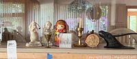 Wide shot showing all items behind glass including figurines, trophies, nesting doll, penny, and candle holder