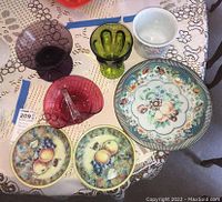 Top view of metal serving bowls, colored glass bowls, ceramic cache on lace tablecloth.
