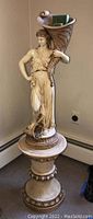 Full height view of statue with woman holding cornucopia and matching pedestal.