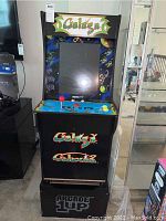 Full front view of Galaga arcade cabinet on riser