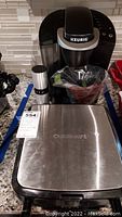 Keurig coffee machine with Cuisinart waffle maker on countertop, image shows front and top view of waffle maker and coffee maker with grinder.
