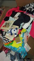 Box showing assortment of children's clothes, toys, and picture frames in various colors and patterns