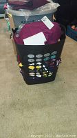 Laundry basket filled with assorted tank tops and small stack of folded tank tops revealing tags and colors