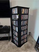 Full view of assembled black rotating shelving unit loaded with movies