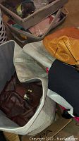 Photo showing gray fabric large bag containing brown leather purse and other items inside.