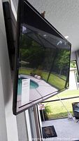 Side view of 33-inch Vizio TV showing black bezel and screen reflecting outdoor pool and patio area.