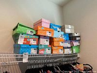 Wide shot of stacked shoe boxes on shelf showing multiple brands and sizes.