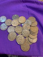 Pile of 28 bronze large cents featuring the seated figure (reverse) laid on a purple cloth.
