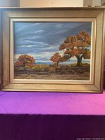 Full view of framed oil painting on board showing landscape with trees and blue sky.