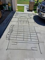 Black metal trellis and garden decor pieces laid out on driveway showing various styles and sizes.